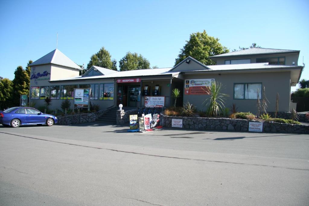 Taupo Debretts Spa Resort Экстерьер фото The photo shows a building that appears to be a business or service center. It features a modern design with a peaked roof and a prominent entrance. The front is landscaped with some greenery, and there are signs displaying various services or busine