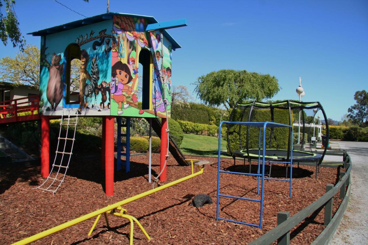 Taupo Debretts Spa Resort Экстерьер фото The photo shows a colorful playground structure that resembles a small house. It features a mural with animated characters on one side, likely including familiar children's figures. The house has ladders for climbing and a slide. Nearby, there is a c